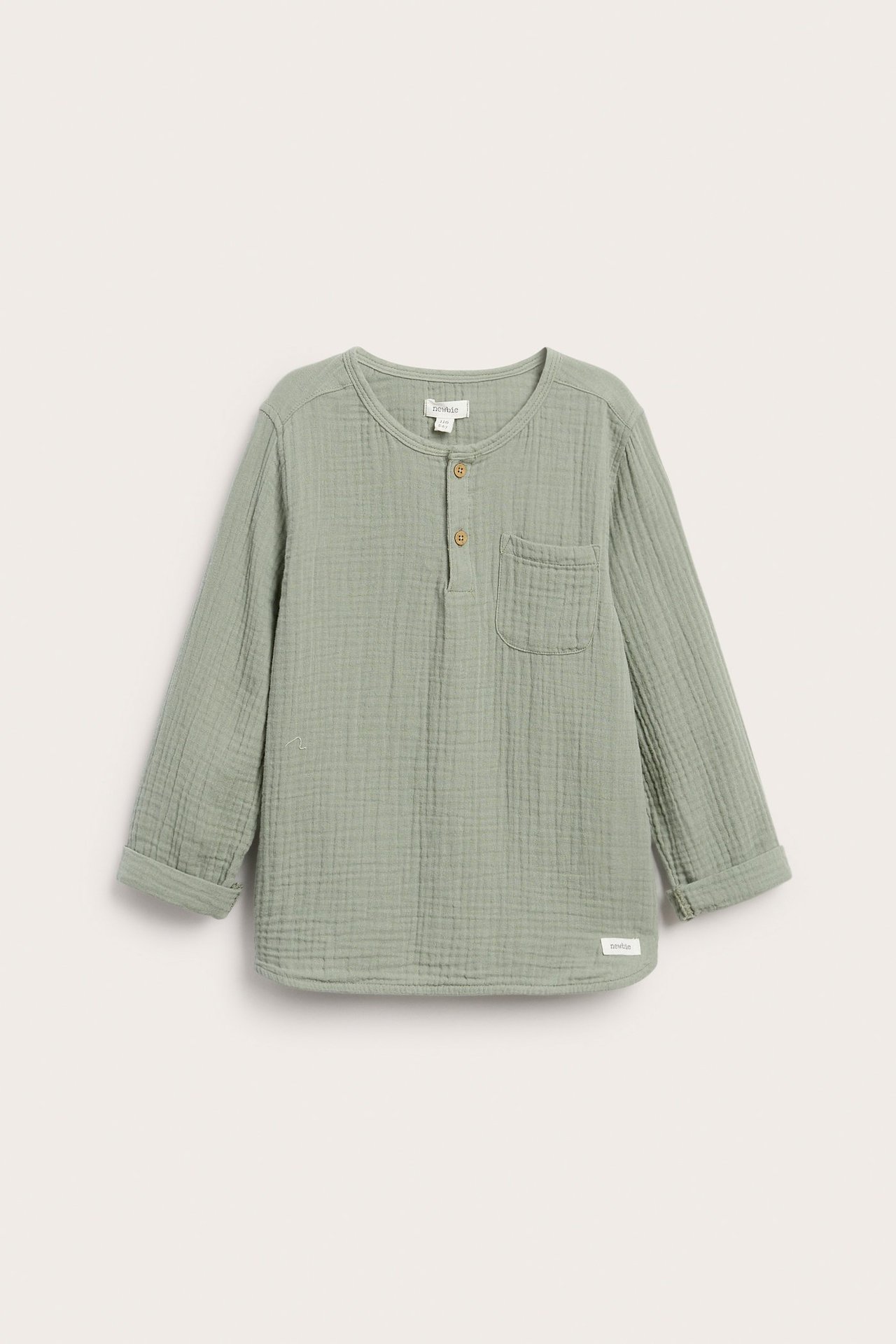 Framifrån: Långärmad topp i mörkgrön muslin för barn, med knappar, bröstficka, upprullade ärmar.