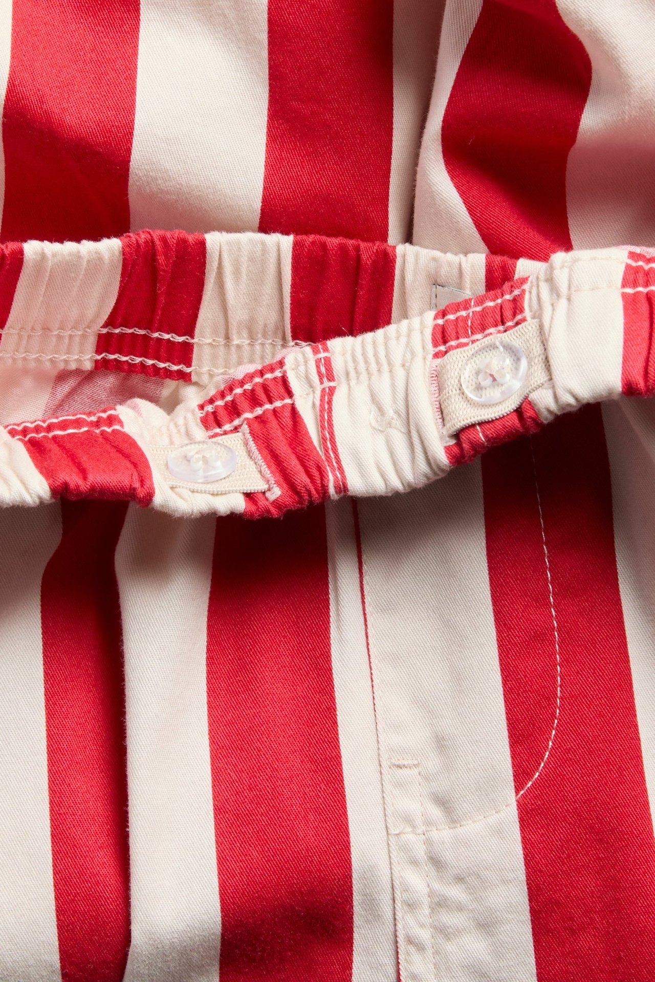 Zbliżenie dziecięcych czerwono-białych pasiastych spodni bawełnianych z regulowaną talią.