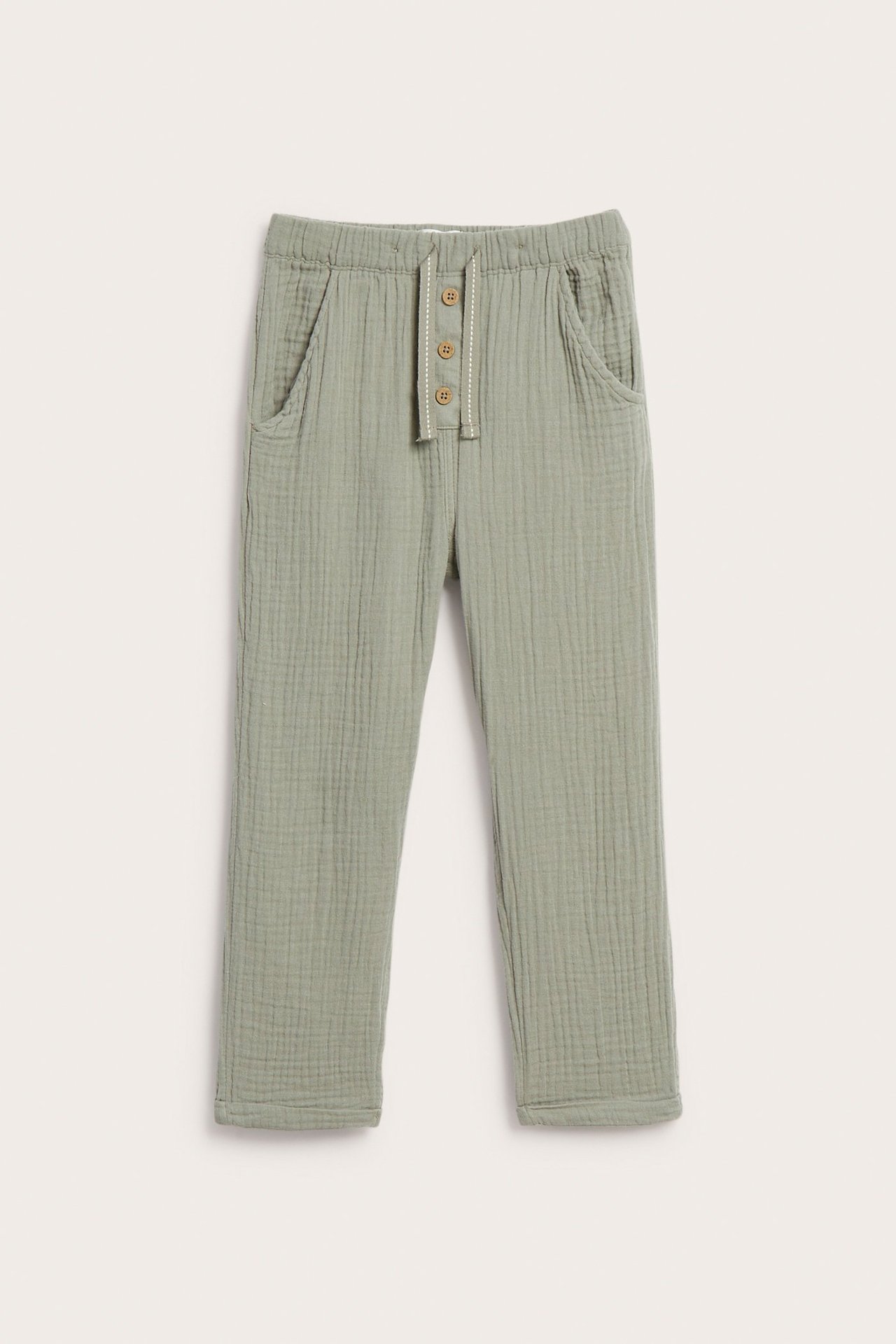 Widok z przodu: Zielone spodnie muślinowe z elastycznym pasem, ozdobnymi guzikami i kieszeniami.