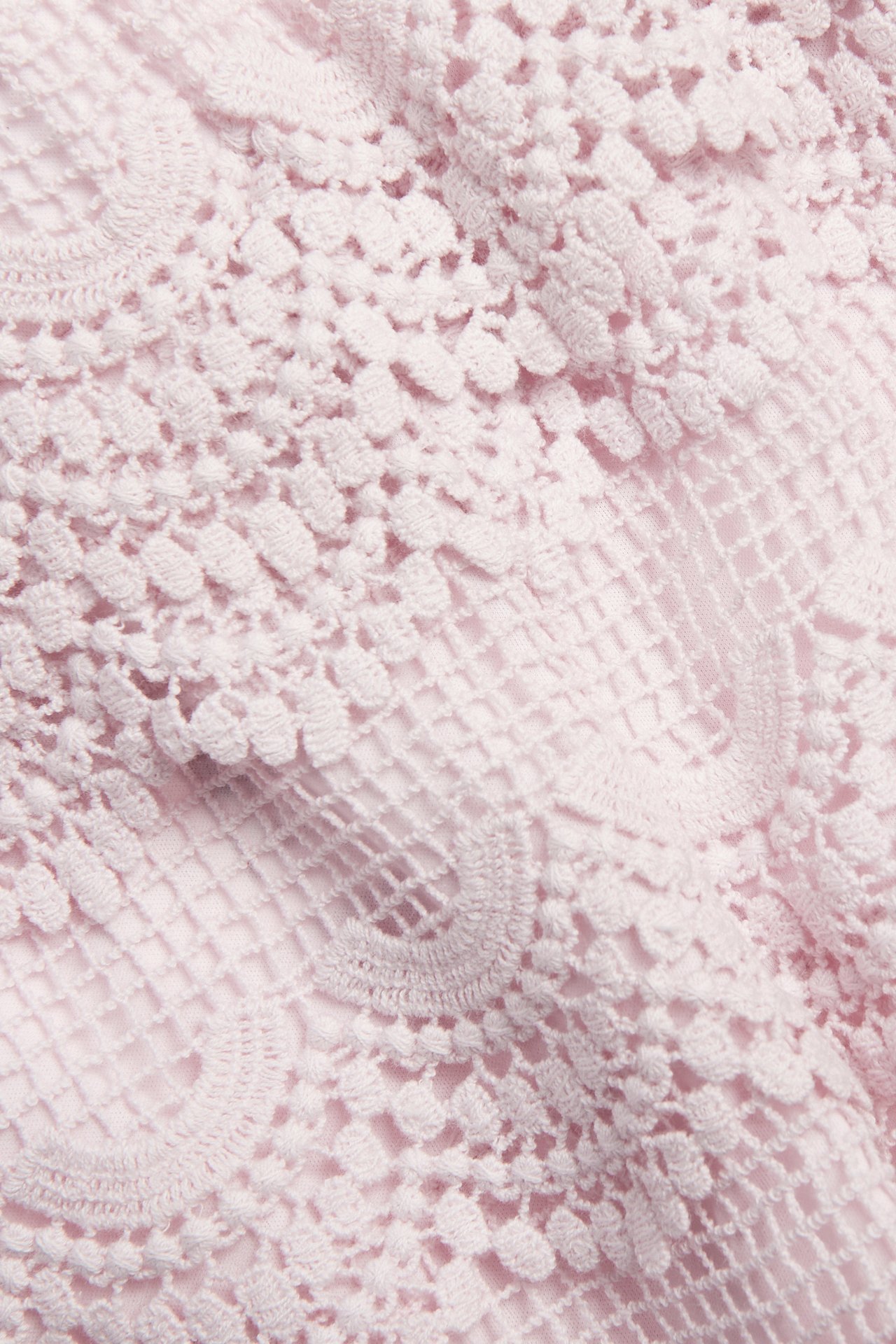 Zbliżenie na jasnoróżowe koronkowe szorty z detalicznym koronkowym wzorem.