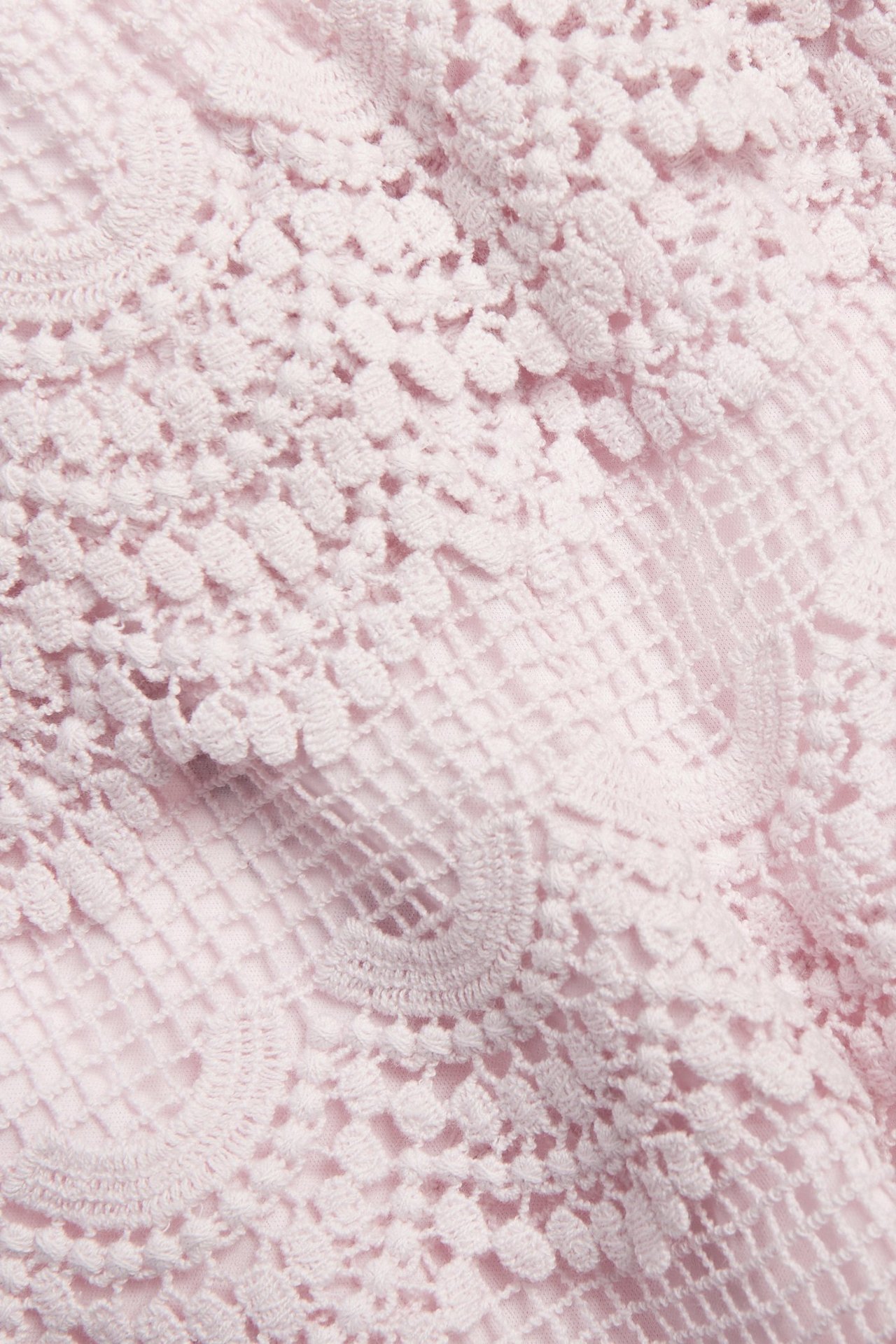 Zbliżenie na jasnoróżowe koronkowe szorty z detalicznym koronkowym wzorem.