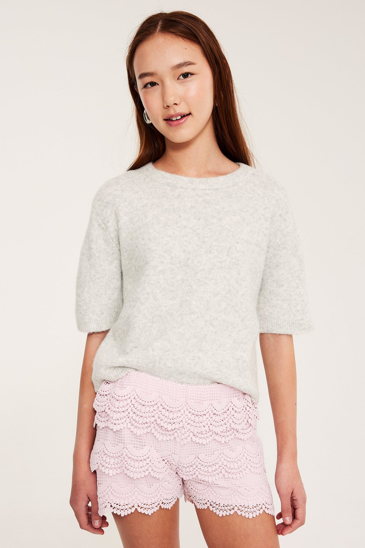 Jasnoróżowe spodenki z koronką, z elastycznym pasem, noszone przez młodą kobietę.