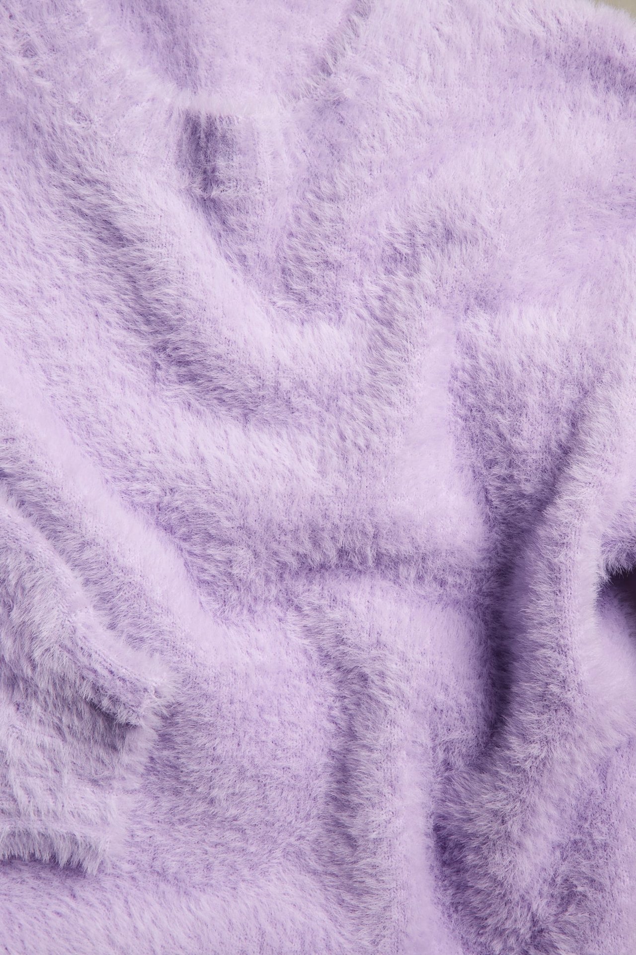 Närbild på en ljuslila fluffig stickad tröja.