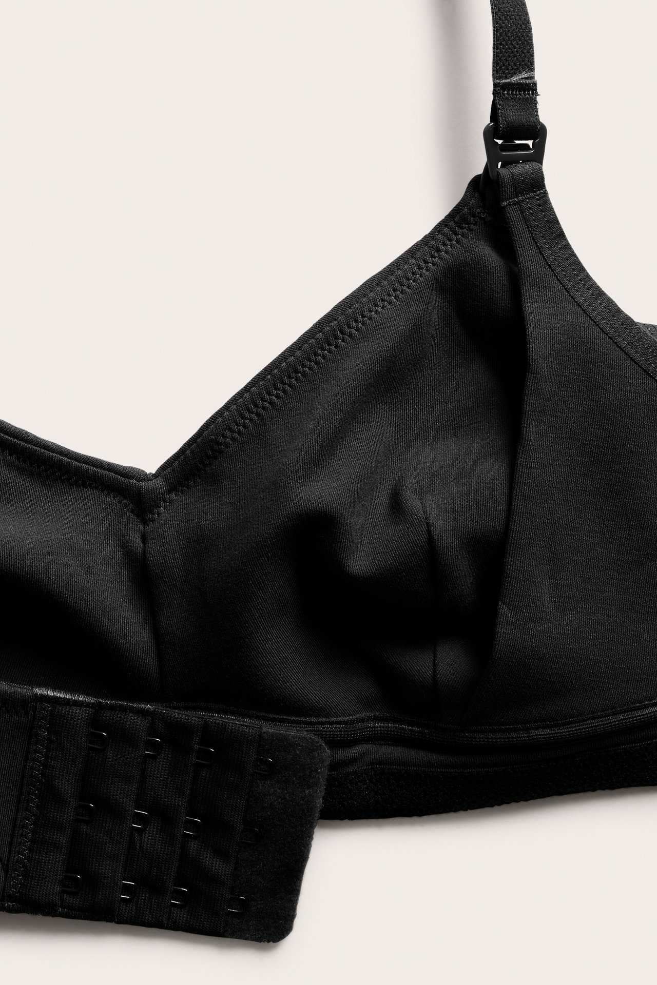 Närbild på en svart amnings-bh i bomullsblandning med justerbar remklämma och hyskknäppning.
