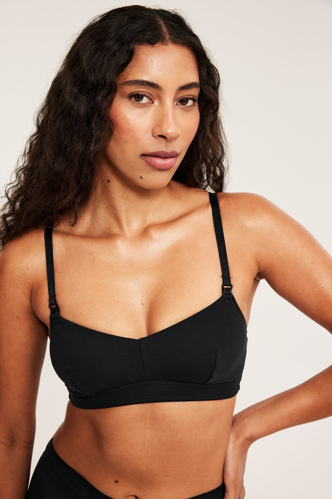 Zbliżenie, widok z przodu kobiety w czarnym, bawełnianym biustonoszu do karmienia z regulowanymi ramiączkami.