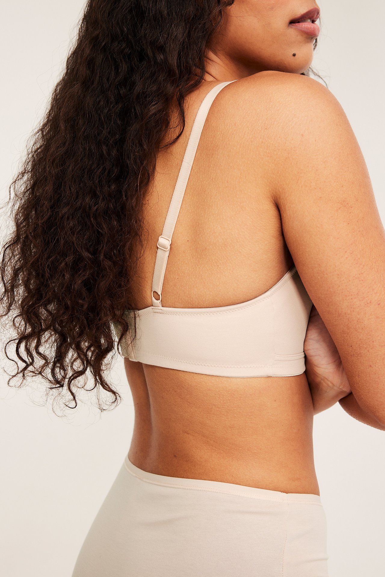 Sidebilde av en kvinne som har på seg en lys rosa bomulls amme-BH og matchende truse.