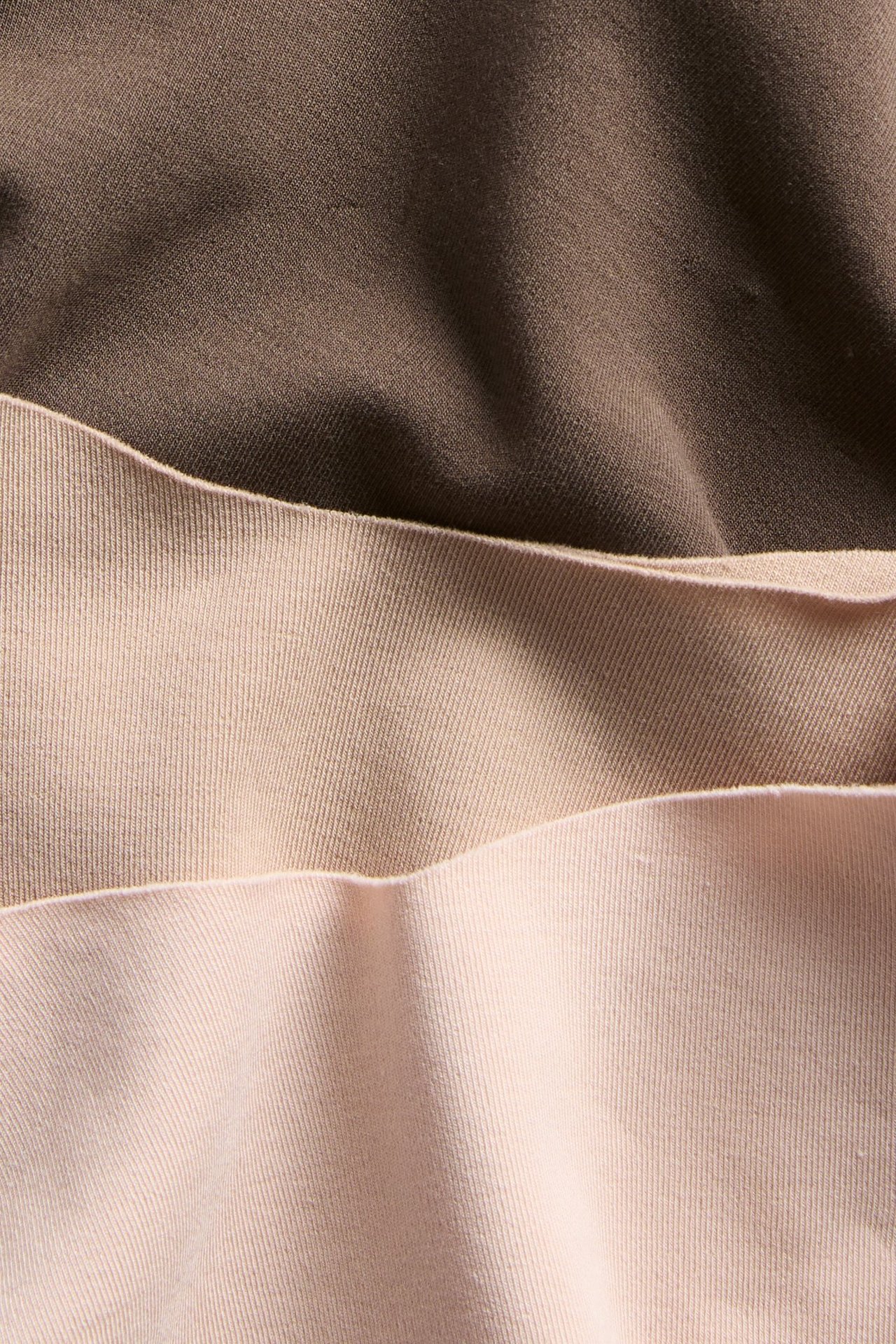 Nærbilde av tre sømløse damestringtruser i lys brun, beige og lys rosa bomullsblanding.