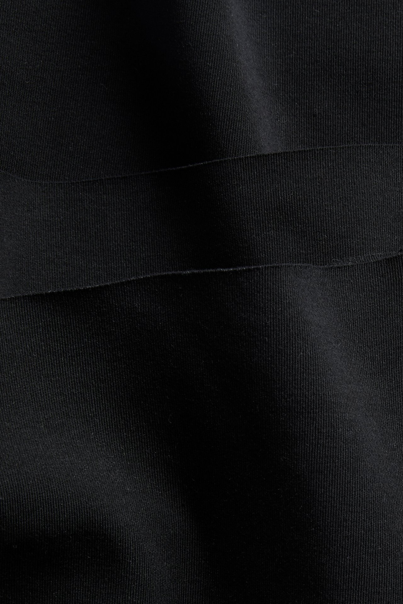 Närbild på svart, mjukt, stretchigt bomullsmix-tyg från boxertrosor med synlig söm.