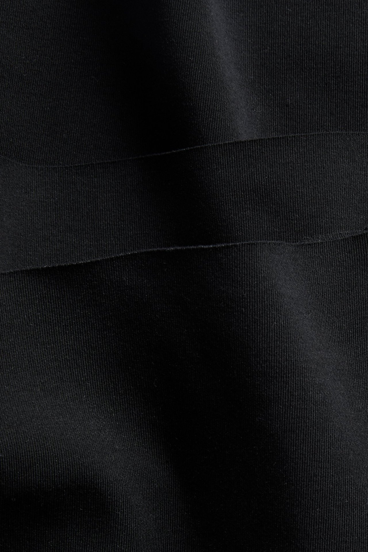 Nærbilde av svart, mykt, tøyelig bomullsblandingstoff fra boksershorts med synlig søm.