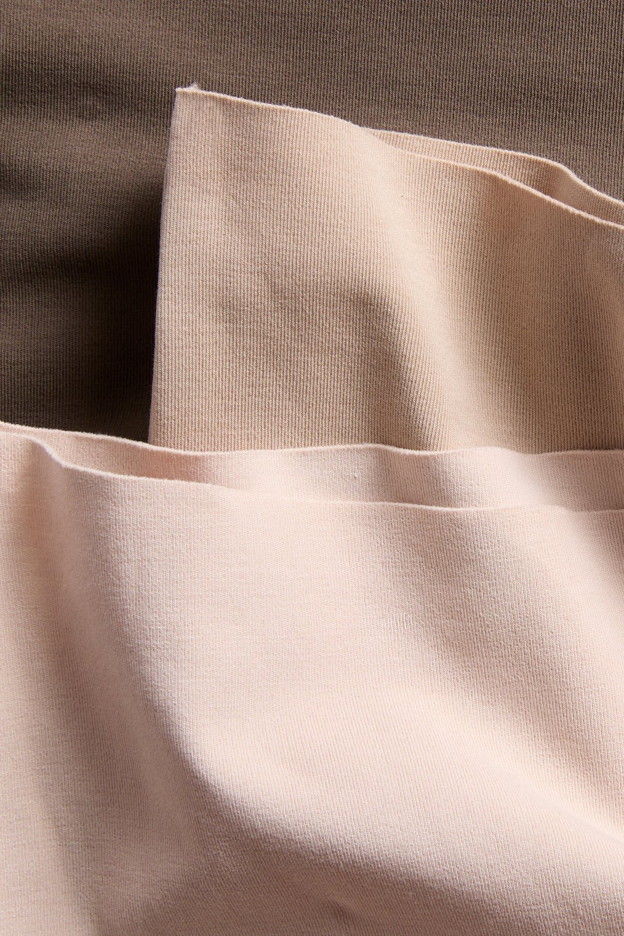 Nærbilde av tre brettede bokser underbukser for dame i lyserosa, beige og brune nyanser av bomullsblanding.