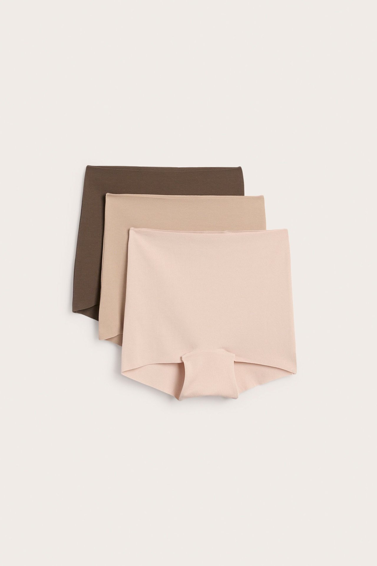 Frontvy av tre sömlösa boxertrosor för dam: ljusrosa, ljusbeige och mörkbruna, i mjuk stretchig bomull.