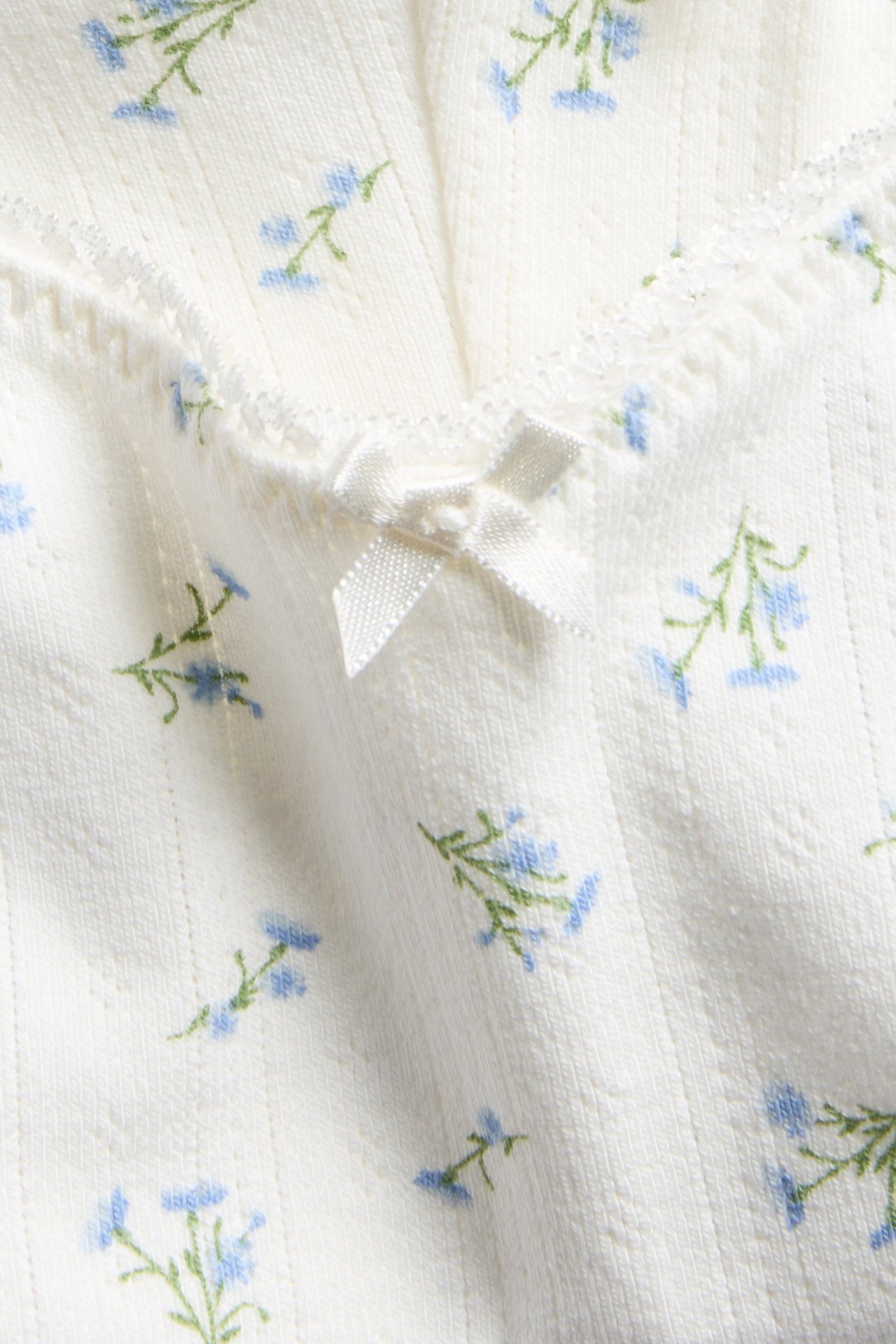 Lähikuva: Luonnonvalkoiset ribatut äitiysalushousut sinisellä kukkakuviolla ja pienellä valkoisella rusetilla.