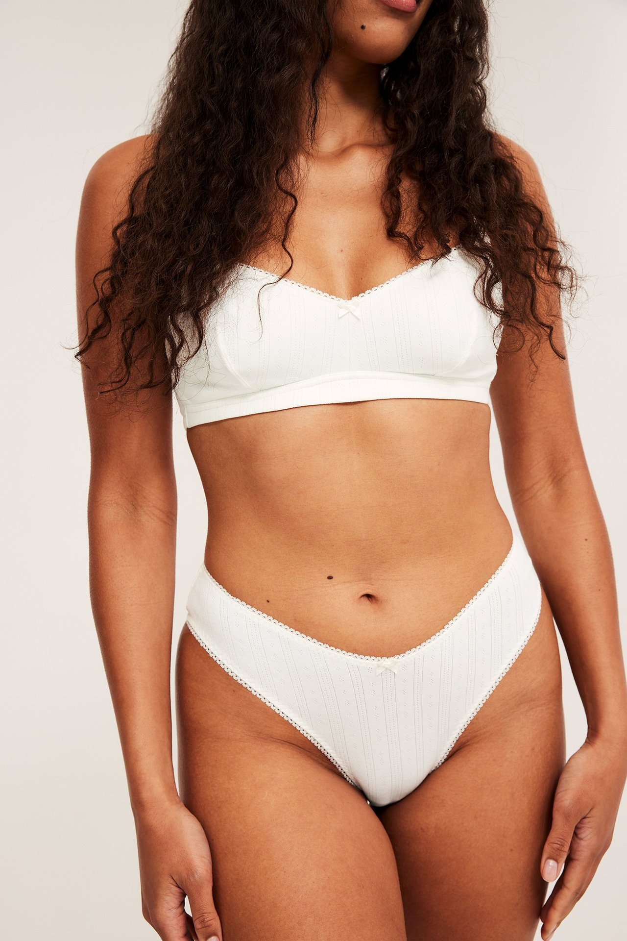 Frontbilde av kvinne i offwhite ribbet mammabrazilian-truse med matchende bralette.