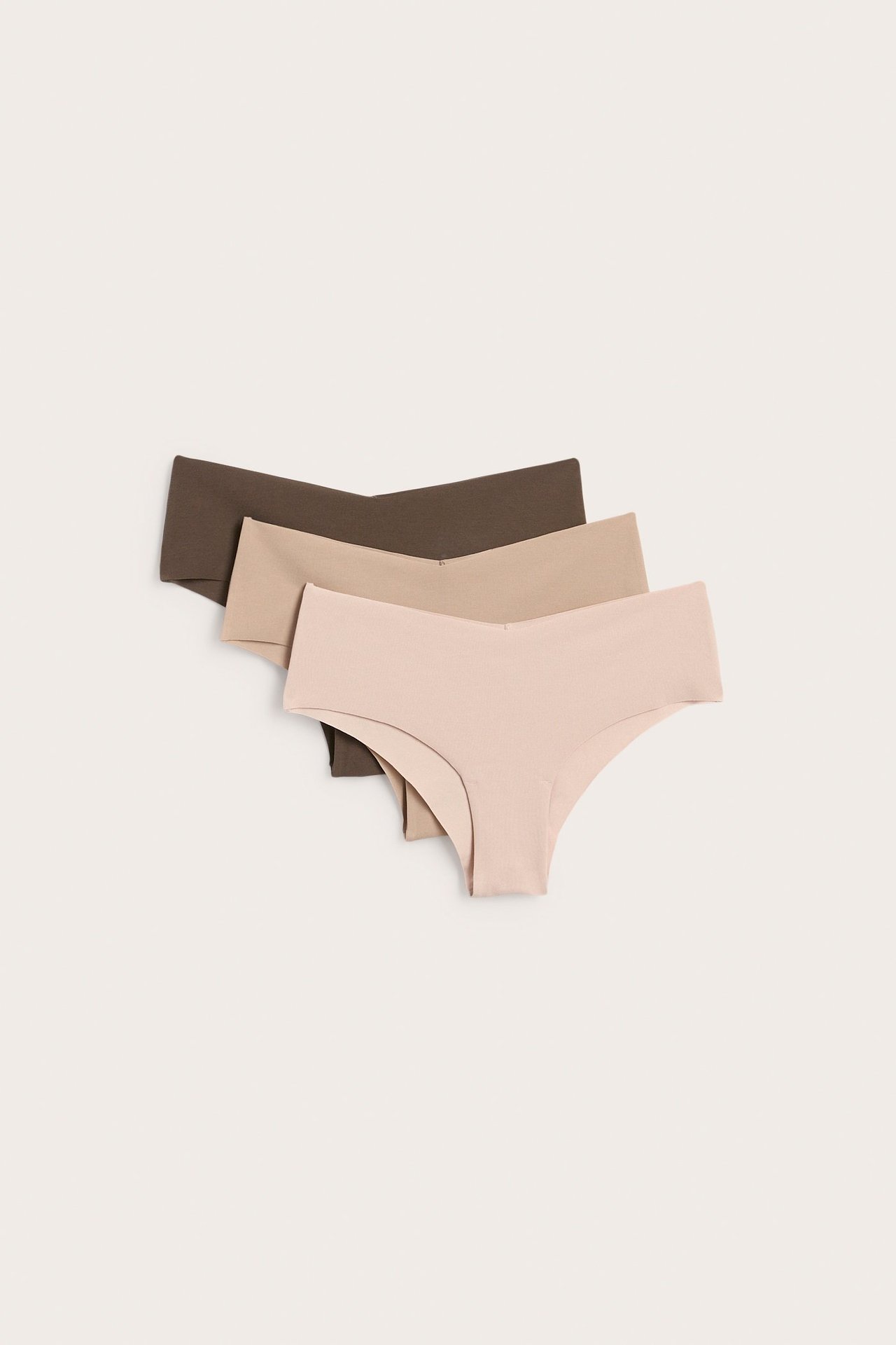 Flat lay av tre sömlösa, lågmidjade mammatrosor i ljusrosa, beige och brunt bomull.