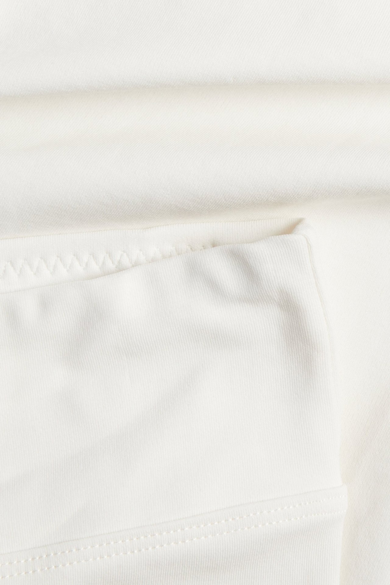 Zbliżenie na białe figi typu szorty z mieszanki bawełny, z szeroką talią i czystym wykończeniem.