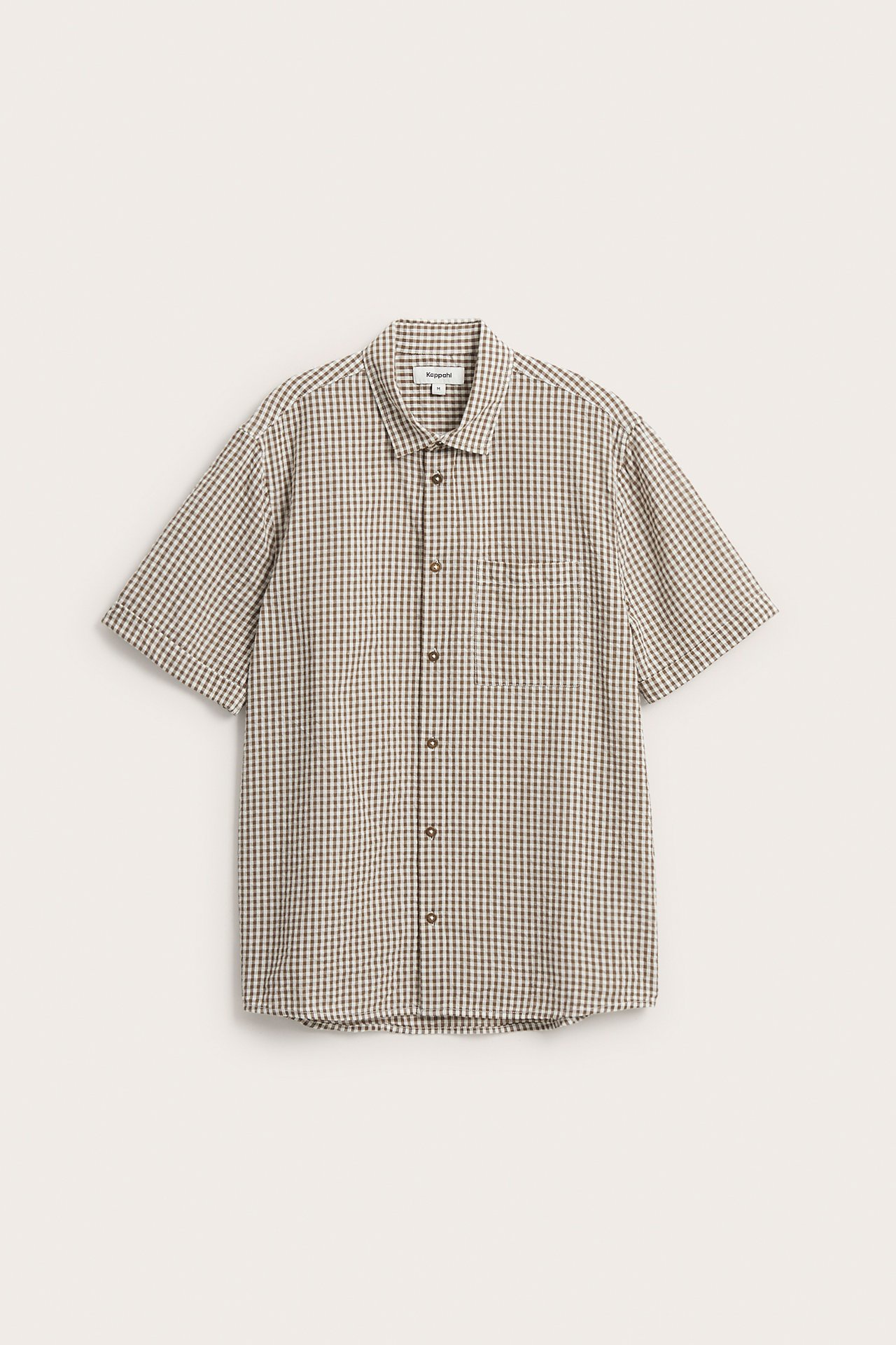 Z przodu: męska jasnobrązowa koszula bawełniana w kratę, krótki rękaw, kieszeń na piersi, guziki.