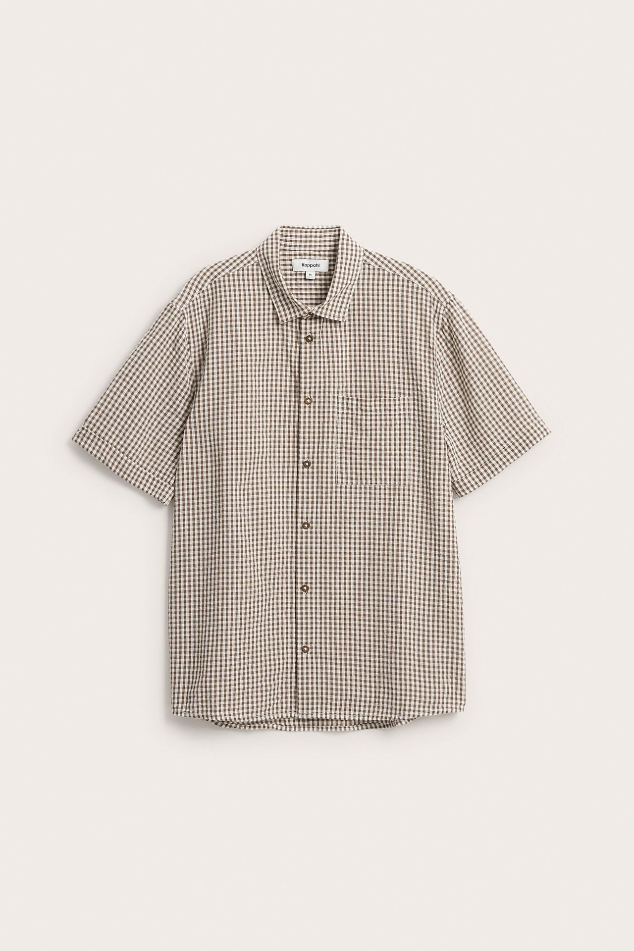 Z przodu: męska jasnobrązowa koszula bawełniana w kratę, krótki rękaw, kieszeń na piersi, guziki.