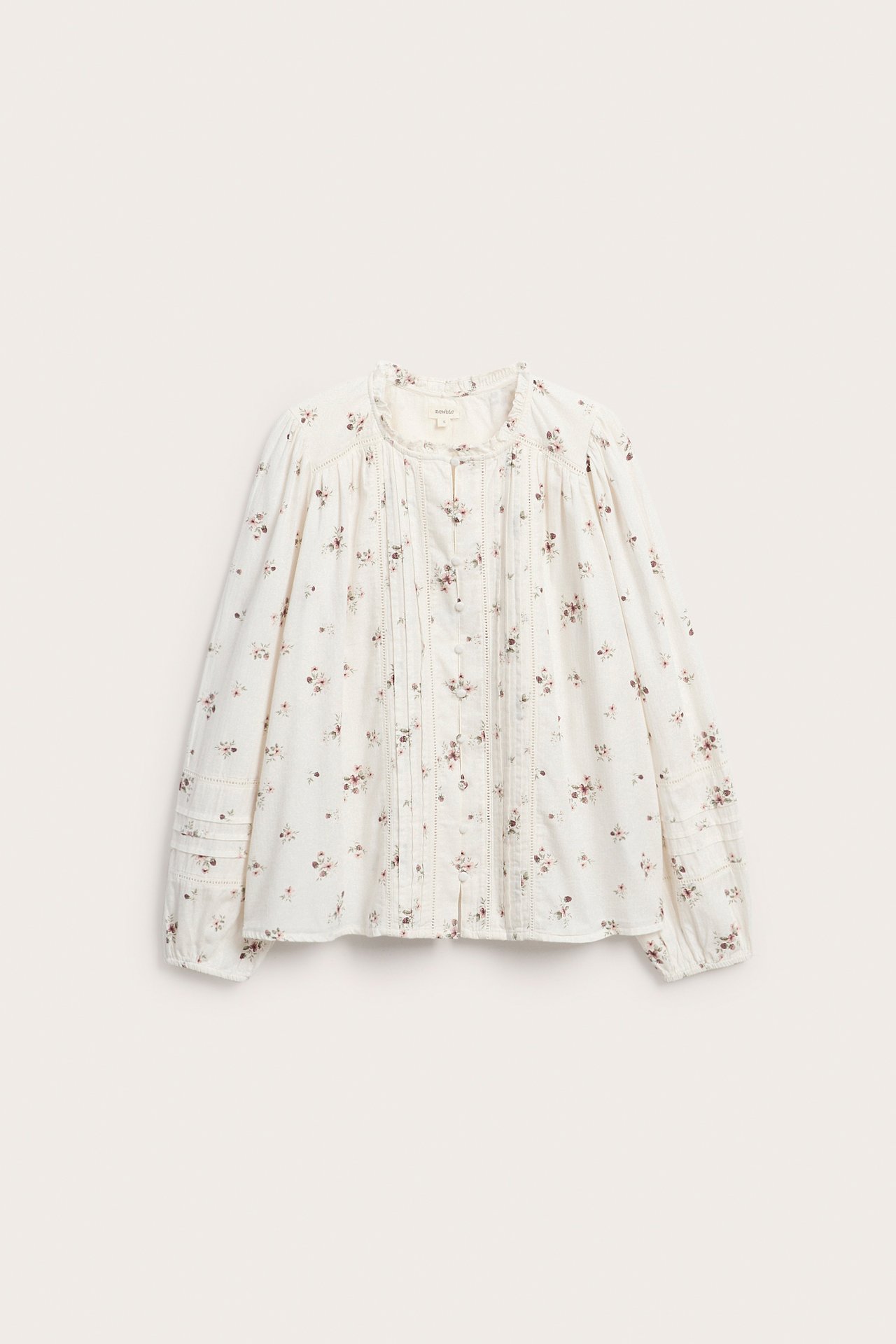 Front: kremfarget bluse med blomstermønster, lange ermer, ryssehals og knappestolpe.