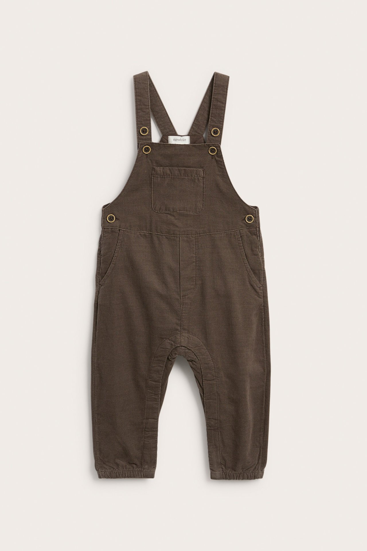 Front av brune kordfløyel baby snekkerbukser med brystlomme og metallfester.