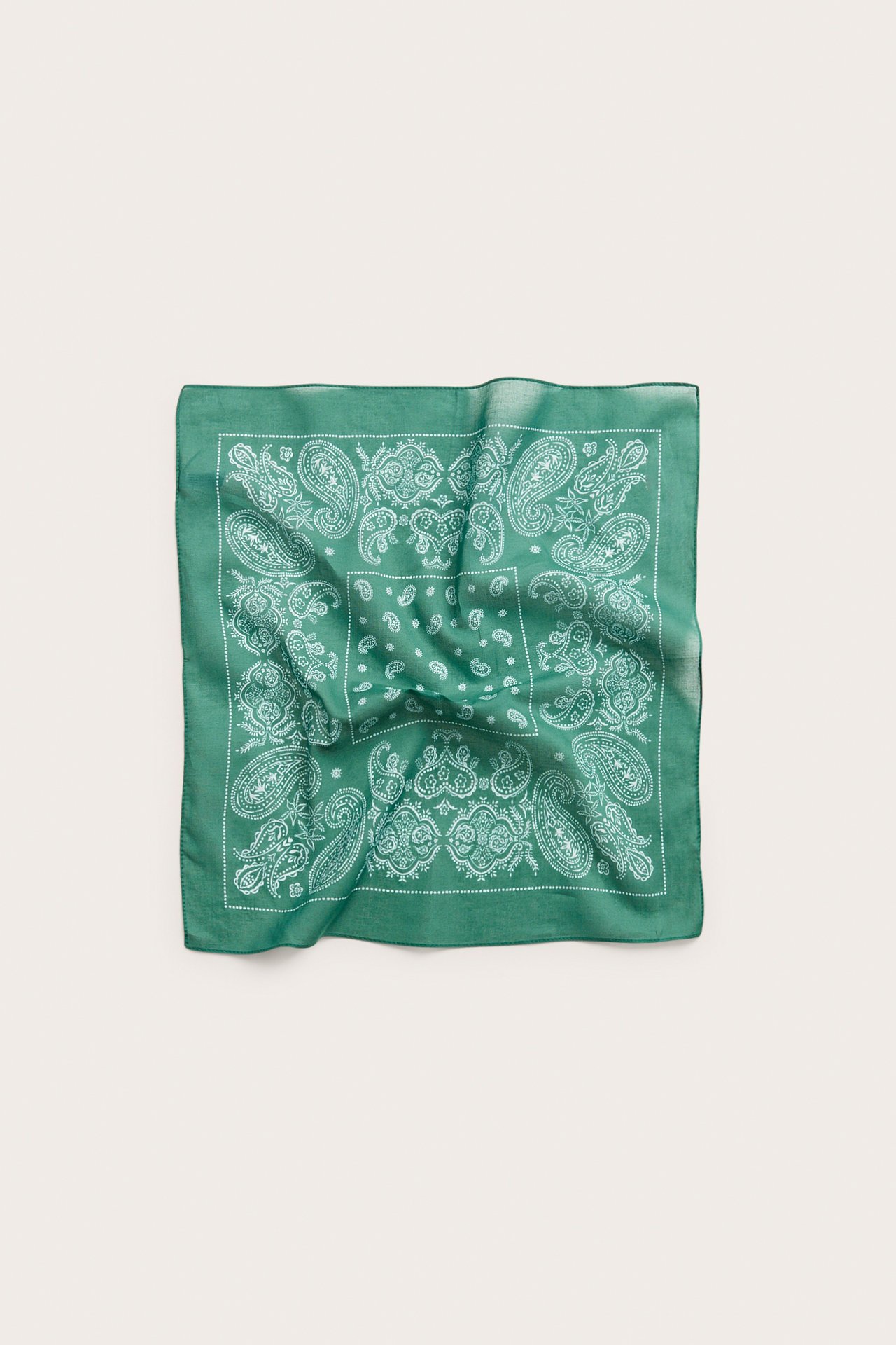 Widok z przodu zielonej, kwadratowej bawełnianej apaszki z białym wzorem paisley.