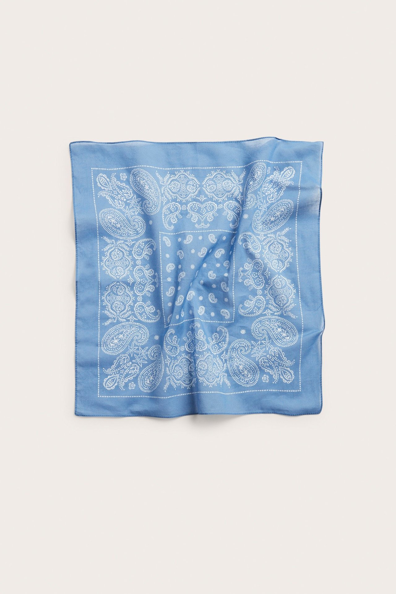 Yläkuva neliönmuotoisesta sinisestä ohuesta puuvillahuivista, jossa valkoinen paisleykuvio.