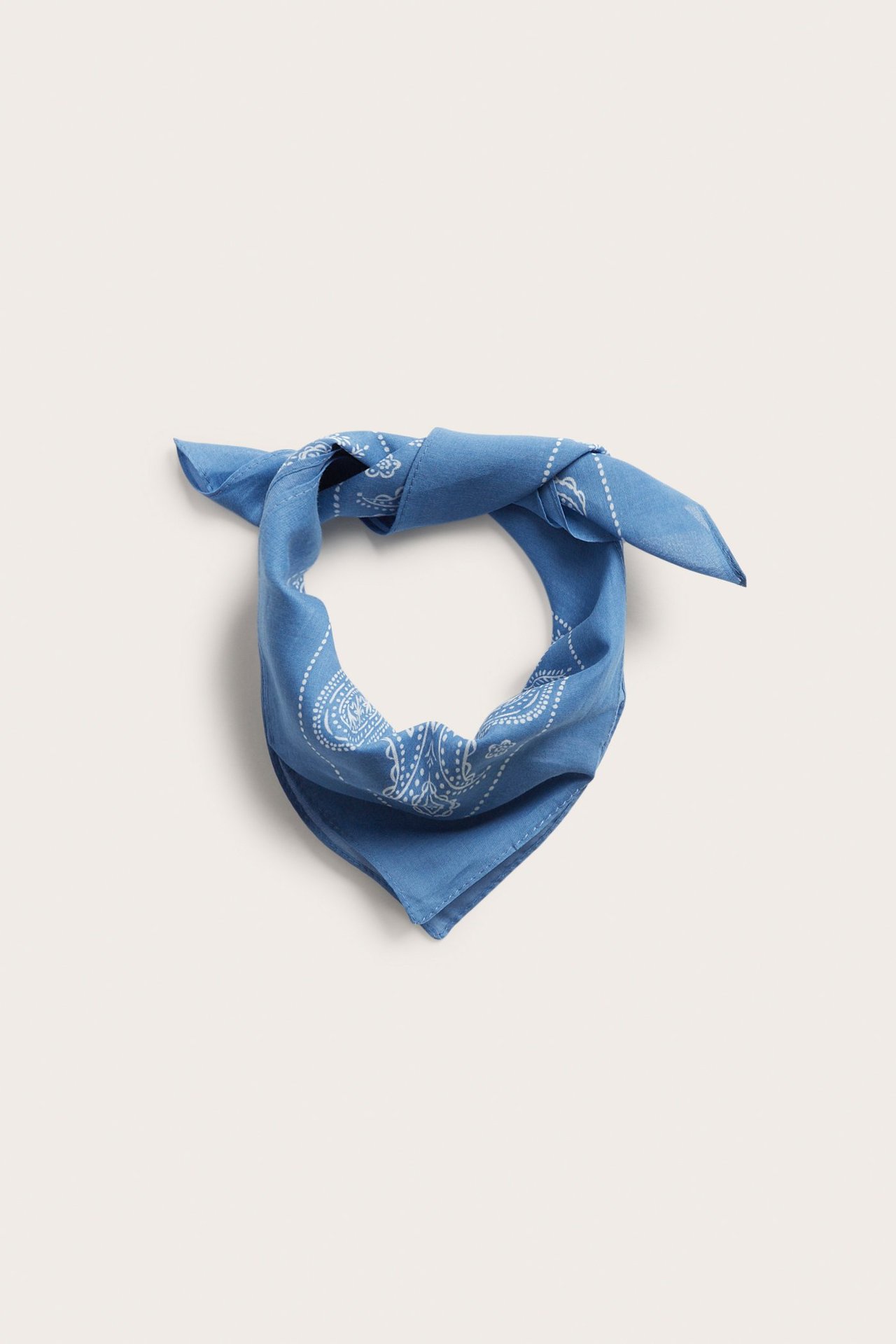 Edestäpäin, sininen ohut puuvillahuivi valkoisella paisley-kuviolla, solmittuna.