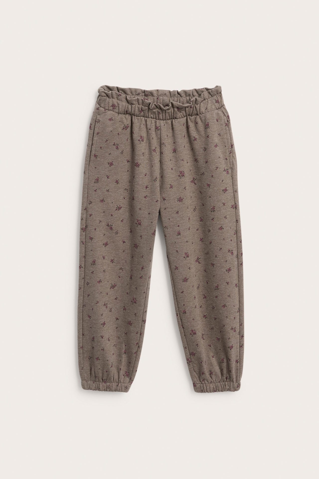 Frontvisning av brune blomstermønstrede joggebukser for barn med elastisk midje og mansjetter.