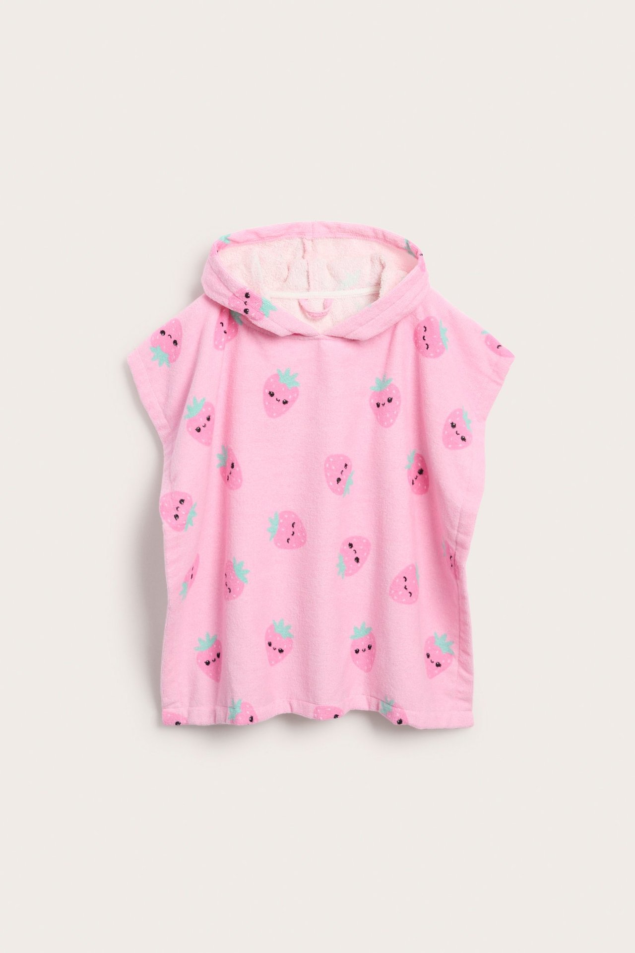 Frontvy av en ljusrosa barnponcho i bomullsfrotté med huva och gulligt jordgubbsmönster.