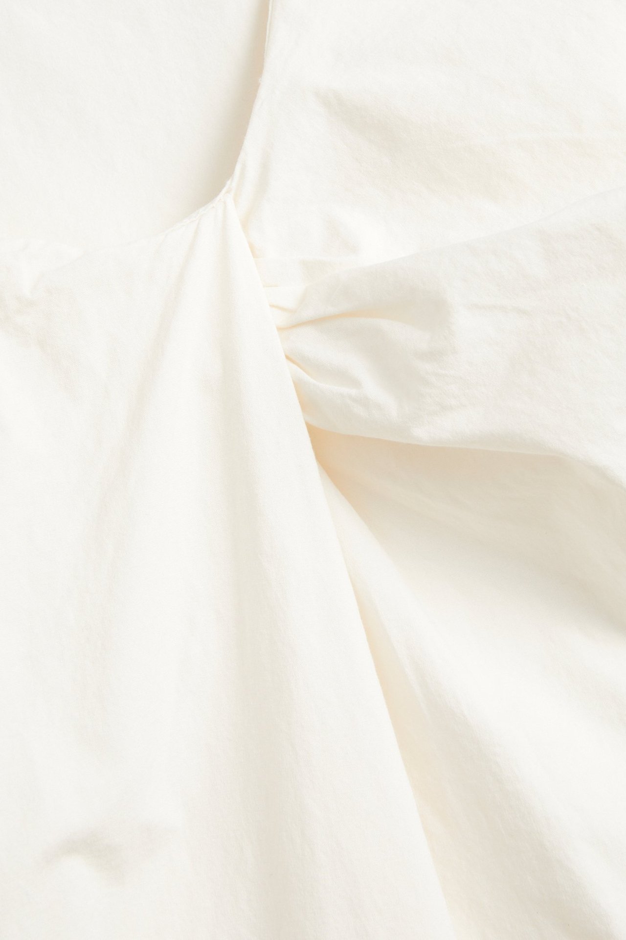 Zbliżenie na biały top z mieszanki bawełny i wiskozy z zakładanym dekoltem.