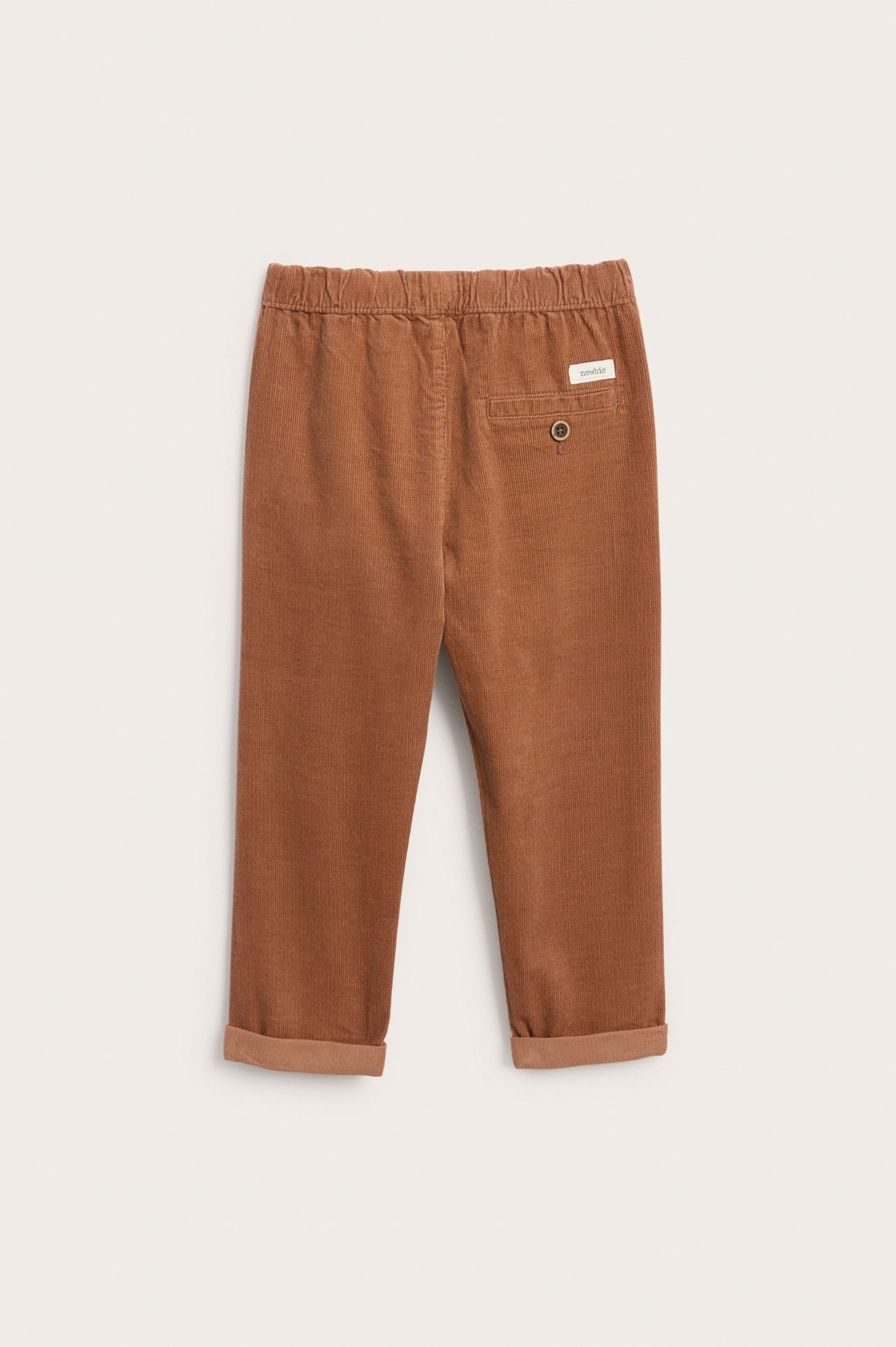 Bakfra brune kordfløyelbukser for barn med elastisk midje, oppbrettede ben og baklomme.