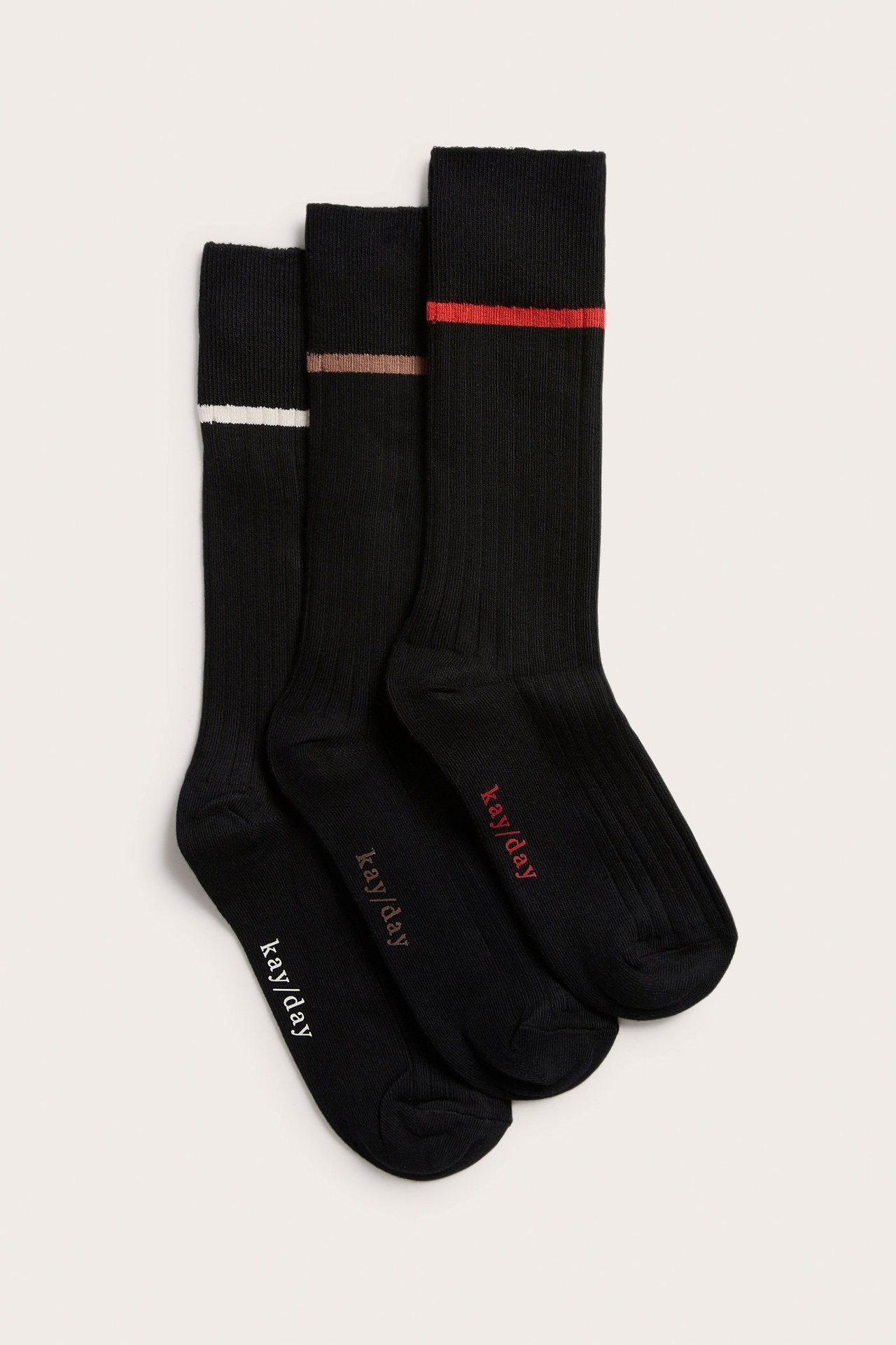 Trzy czarne prążkowane skarpetki z białymi, brązowymi i czerwonymi paskami na ściągaczach. Widok z góry.