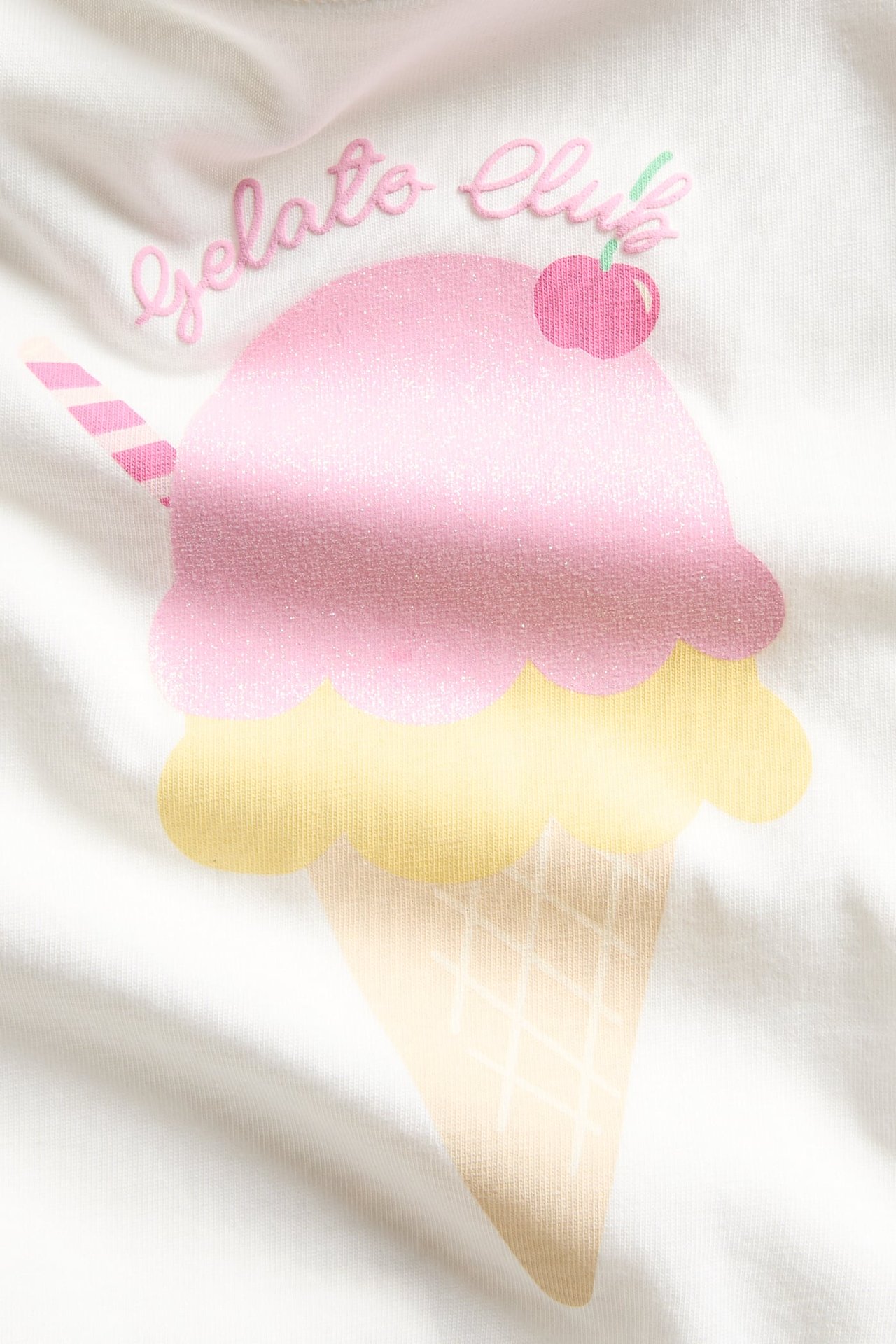 Zbliżenie białego, bawełnianego T-shirtu z różowo-żółtym, brokatowym nadrukiem lodów.