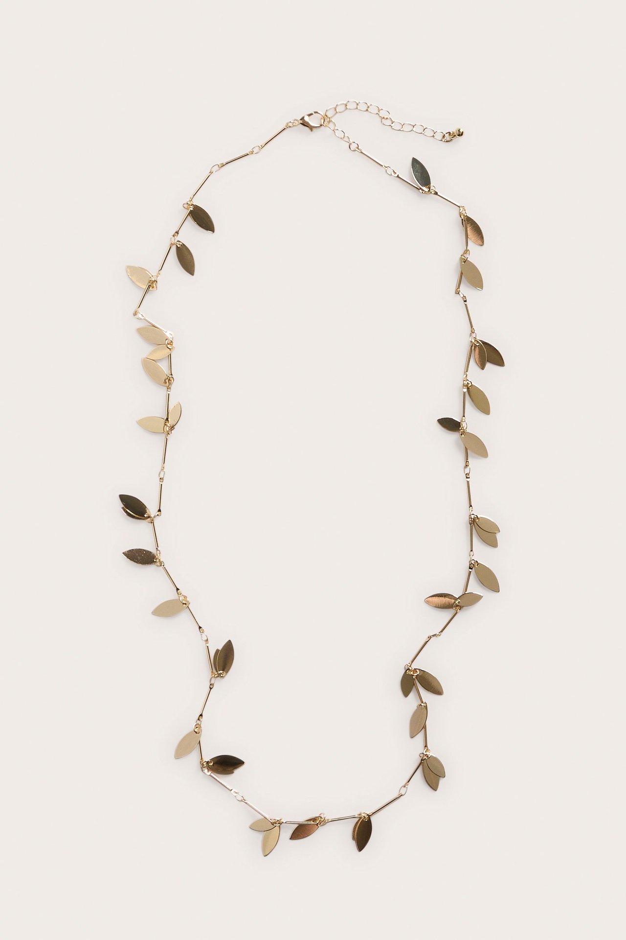 Ylhäältä näkymä pitkästä kultaisesta metallikaulakorusta, jossa on pieniä lehtiä ja säädettävä lukko.