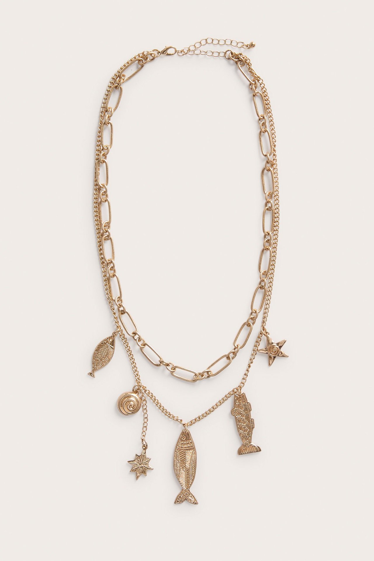 Edestä kuvattu kerrostettu kultainen metallikaulakoru, jossa on merihenkisiä riipuksia, kuten kala, simpukka ja meritähti.