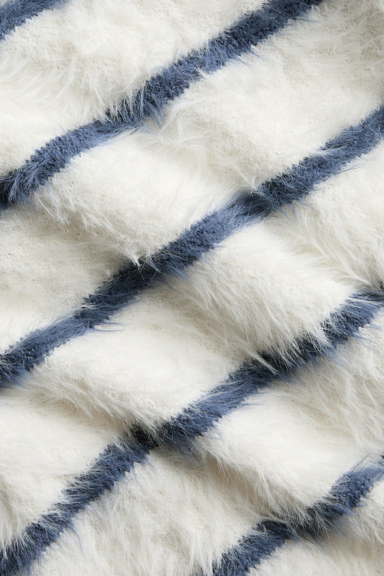 Närbild av en vit och blå diagonalt randig fluffig tröja.