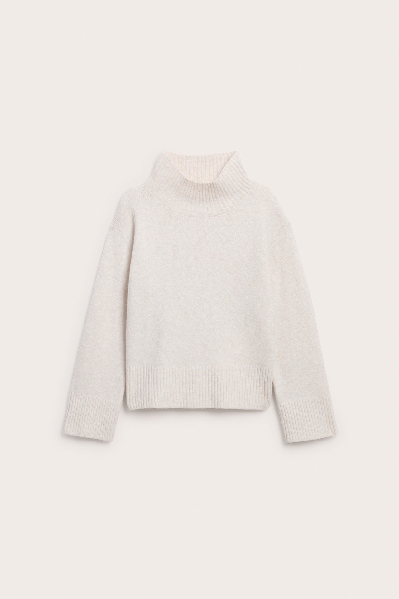 Framifrån, ljusbeige mock neck tröja med ribbade muddar och nederkant.