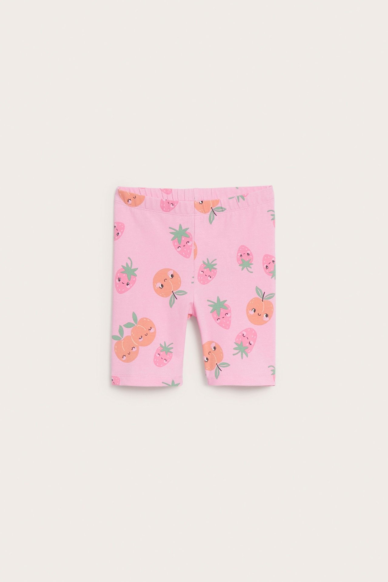 Lasten vaaleanpunaiset puuvillaiset pyöräilyshortsit edestä, joissa hedelmäkuvio ja joustava vyötärö.