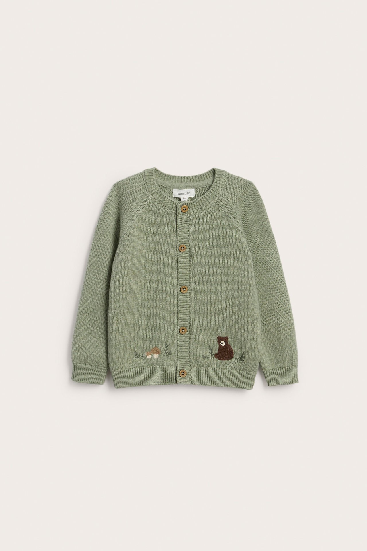 Front: Lys grønn strikket babycardigan med brodert bjørn, sopp og treknapper.