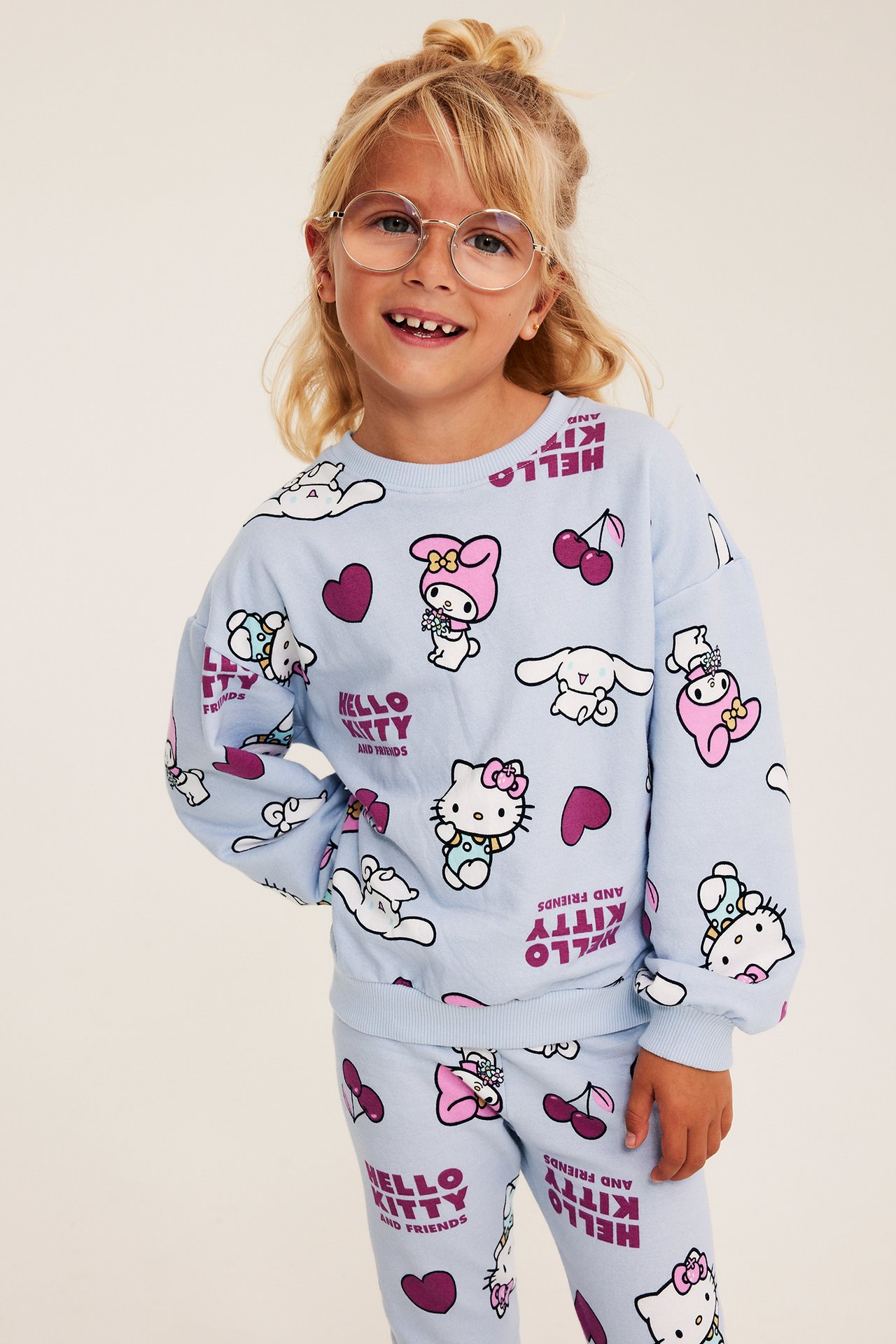 Widok z przodu dziecka w jasnoniebieskiej bluzie z nadrukiem Hello Kitty i przyjaciół oraz pasujących spodniach.