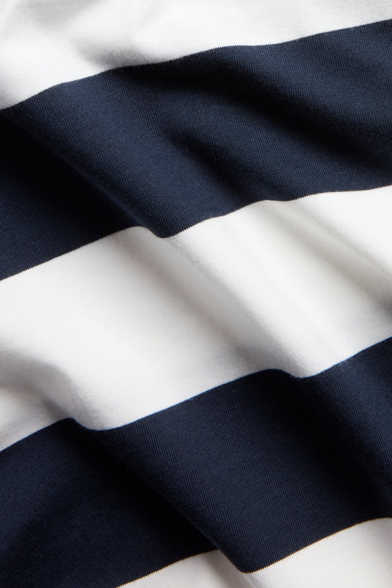 Lähikuva ylisuuresta puuvillaisesta t-paidasta, jossa leveät tummansiniset ja valkoiset raidat.