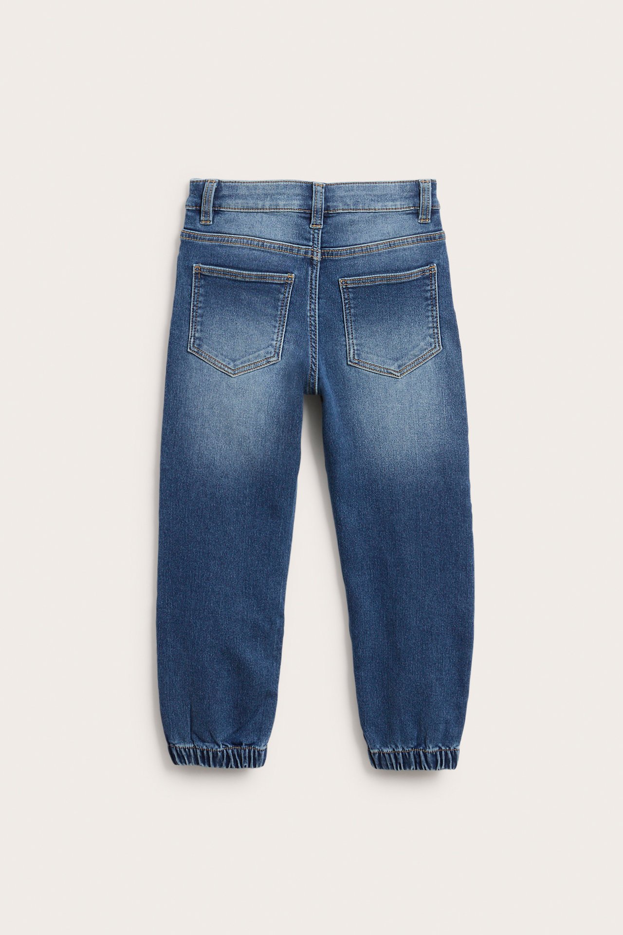 Baksida av blåa denim jogger-jeans för barn med resår i midjan och muddar vid anklarna.