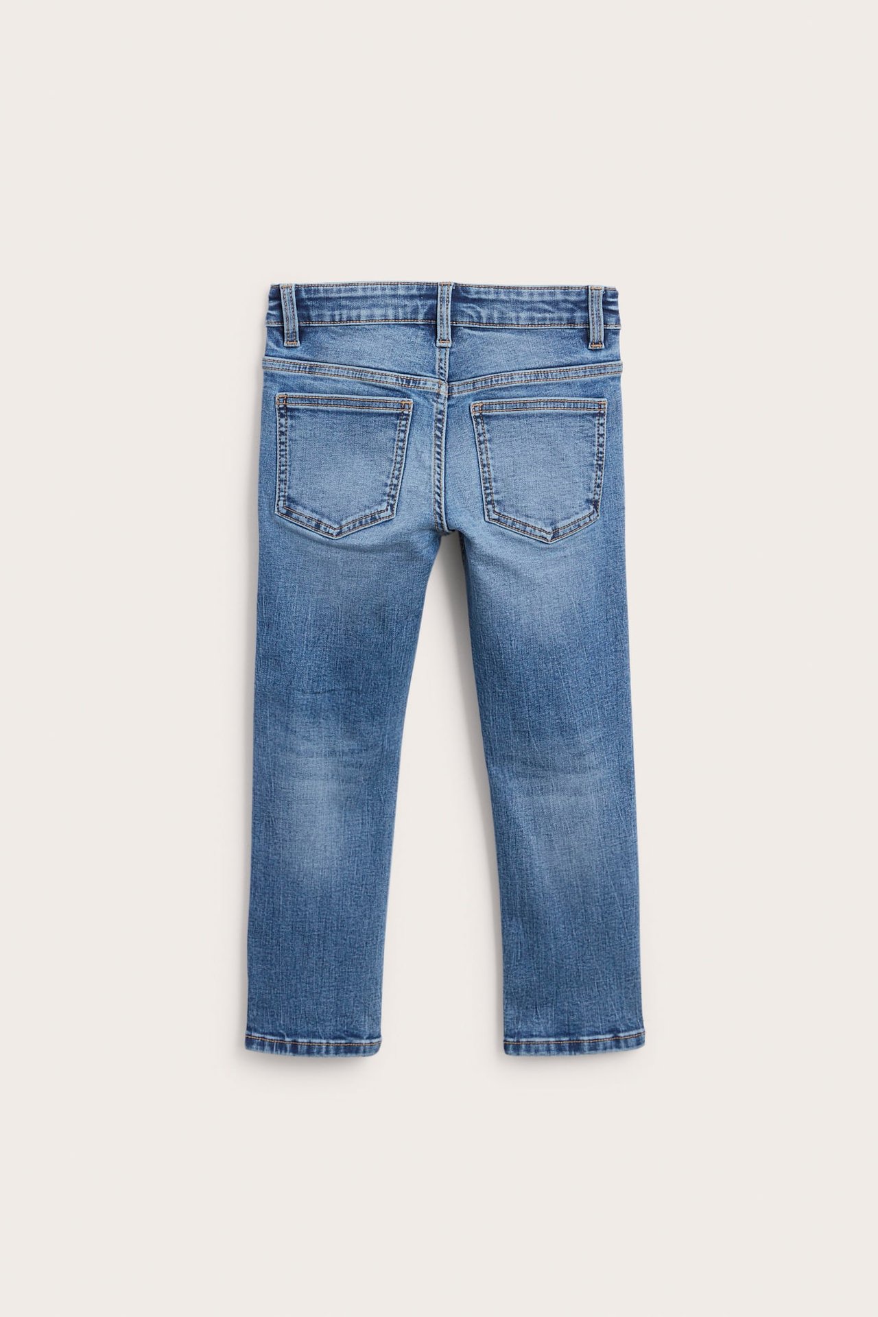 Bakifrån av tvättade blå barnjeans med bakfickor och hällor.
