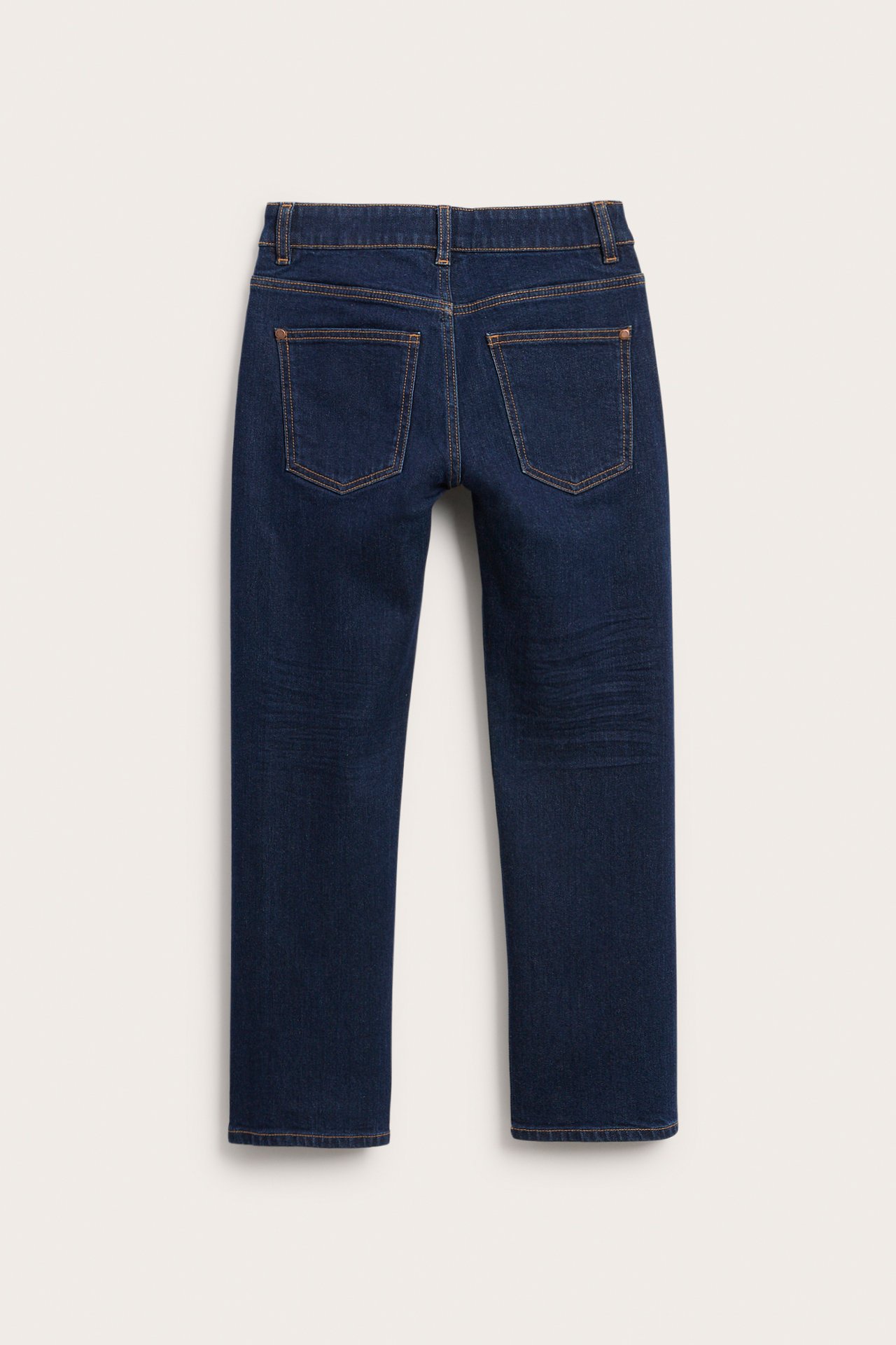 Mörkblå denimjeans med bruna sömmar och bakfickor, bakifrån.