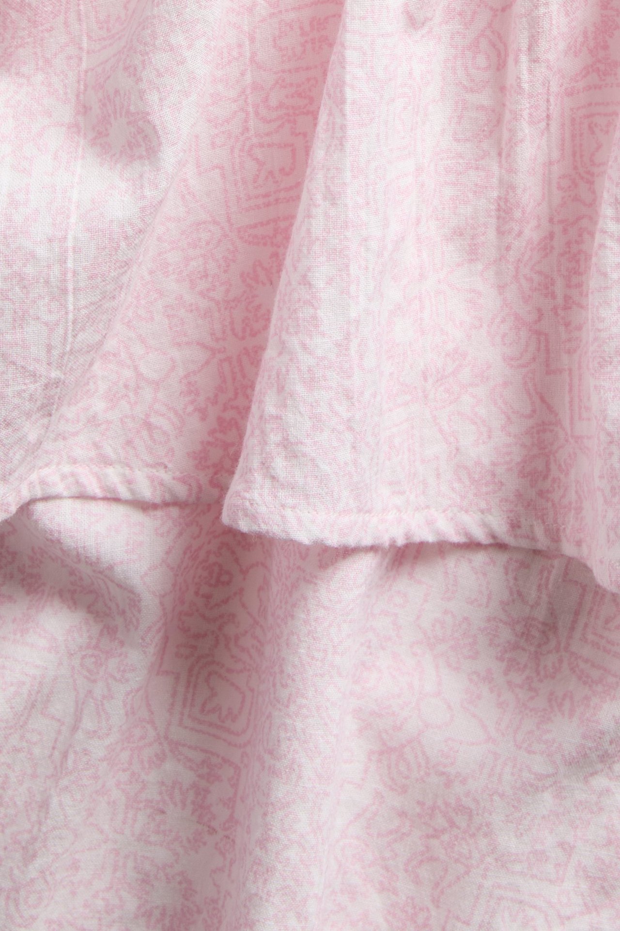 Zbliżenie na różowy, wzorzysty bawełniany top z falbanką.