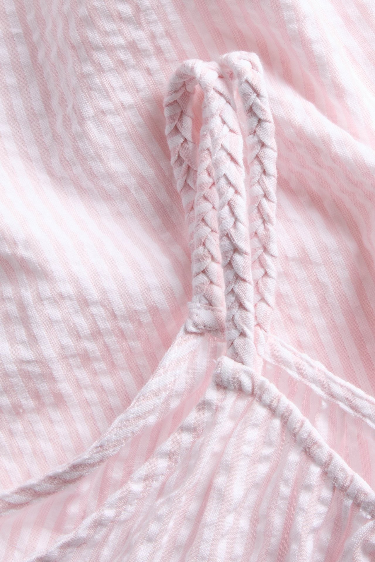 Zbliżenie różowo-białego prążkowanego topu bawełnianego bez rękawów z plecionymi ramiączkami.