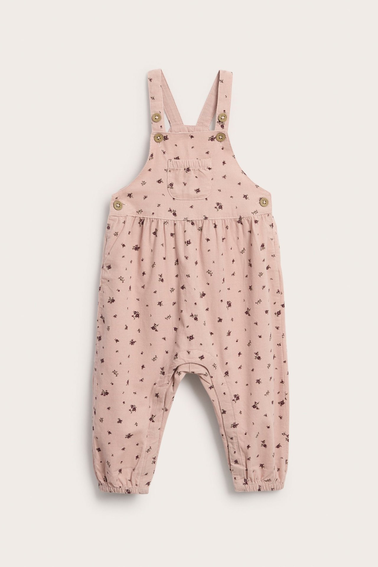 Framifrån, babyrosa blommig overall med knappremmar och framficka.