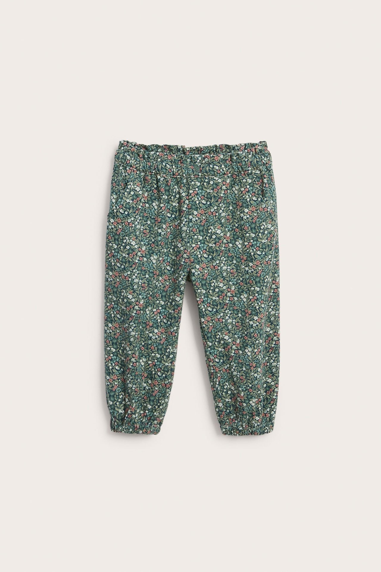 Barnebukser med grønt blomstertrykk, elastisk midje og mansjetter, forfra.