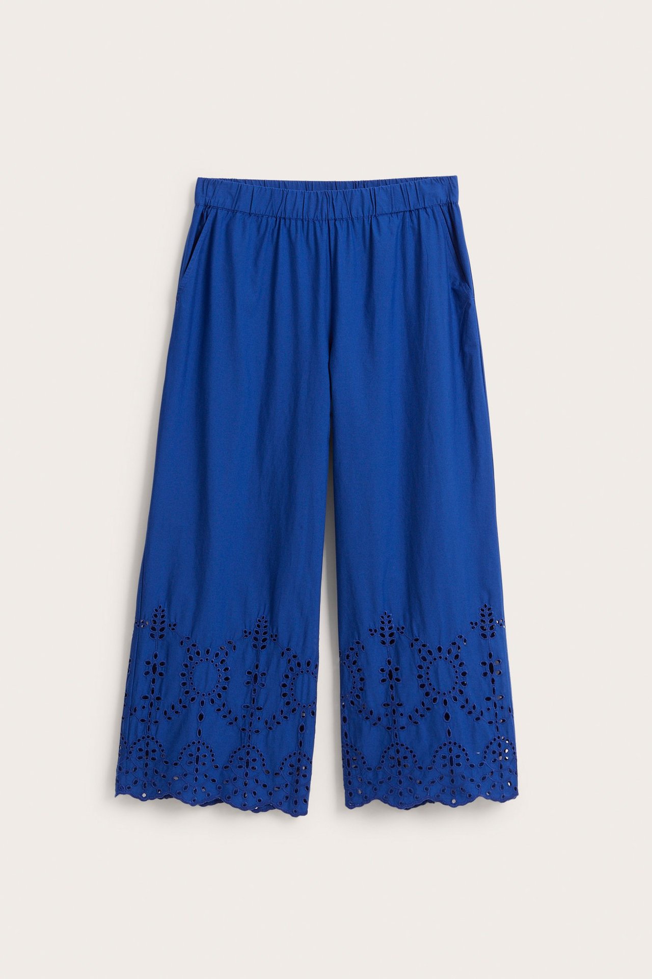 Etunäkymä: Siniset leveälahkeiset puuvillahousut, joustovyötärö, sivutaskut ja brodeeraus anglaise.