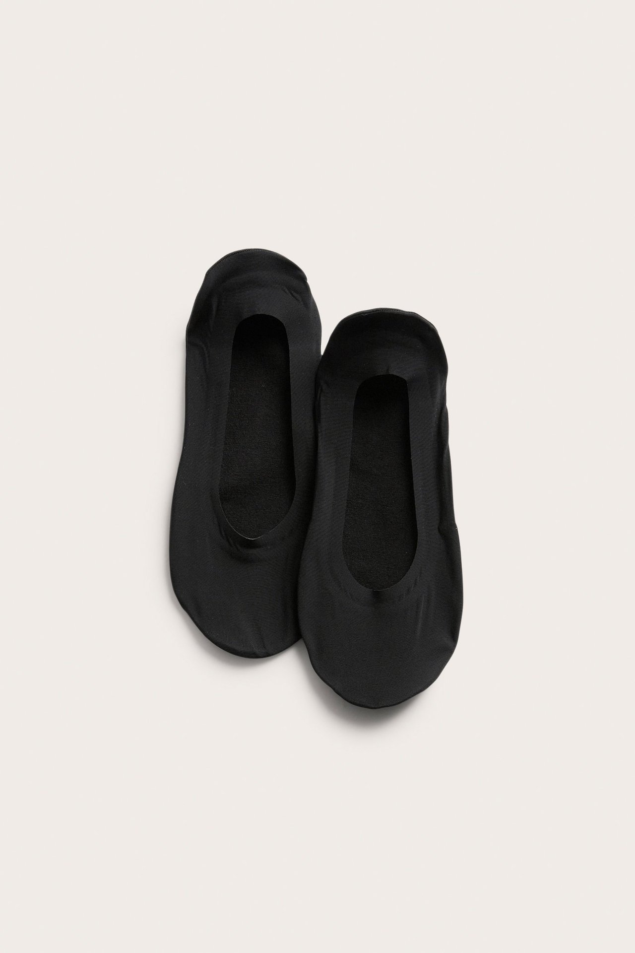 Widok z góry na dwupak czarnych, niskich, niewidocznych stopek z gładkiego materiału.