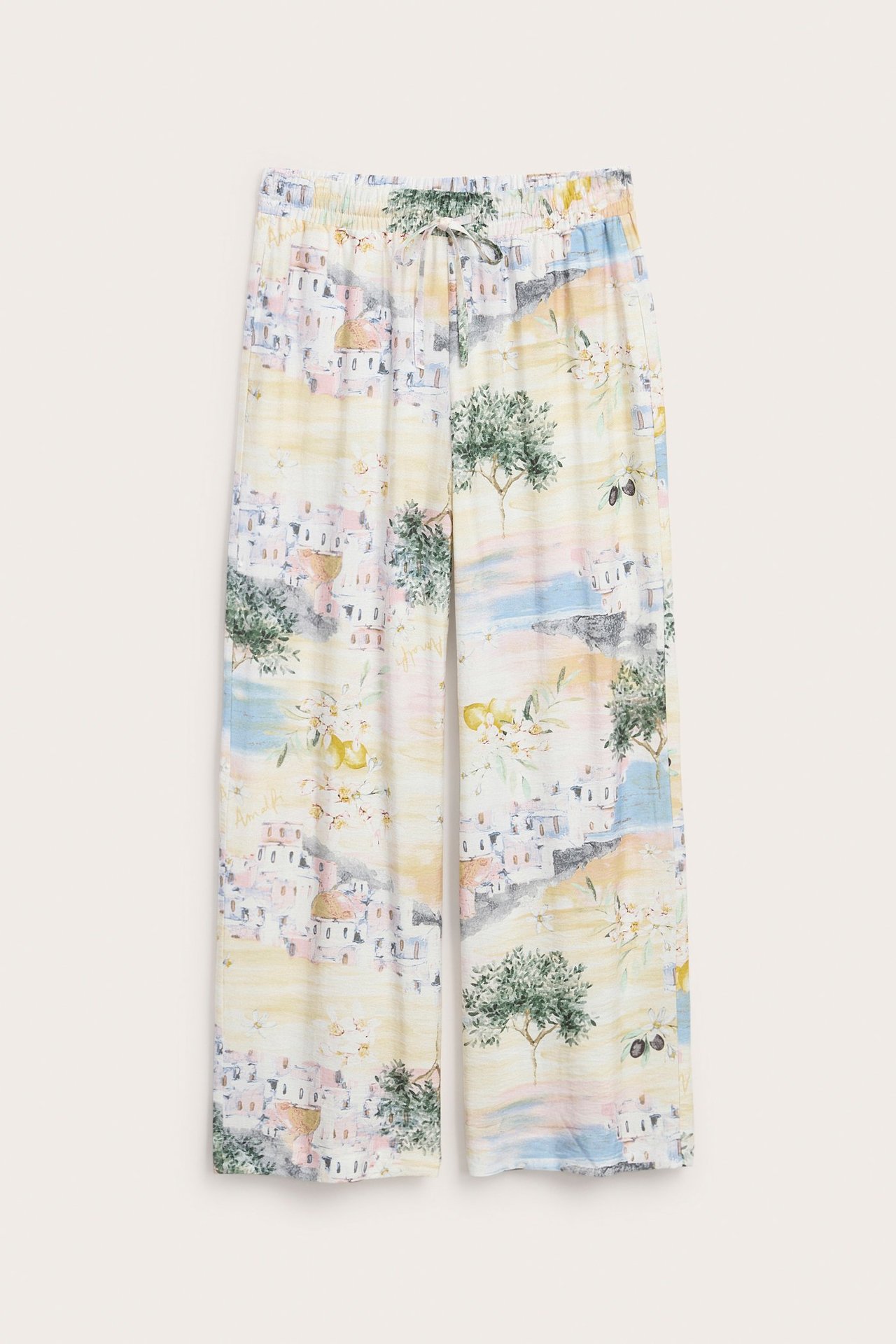 Edestä: Luonnonvalkoiset leveälahkeiset vetohousut, joissa värikäs Välimerikuvio ja kiristysnyöri vyötäröllä.